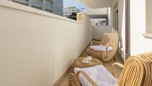 Un balcon agrémenté de meubles en osier, notamment une chaise et une petite table ronde sur laquelle se trouvent une théière et une tasse.
