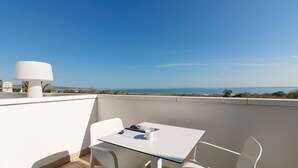 Un balcon avec une table et des chaises, une lampe et une vue sur la mer.