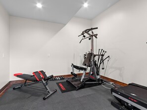 A home gym with a treadmill, weight bench, dumbbells, and a stationary bike. - New Home on South Toe River, Pet Friendly (Burnsville)
