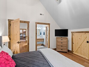 Quarto com cama, televisão, penteadeira e guarda-roupa.