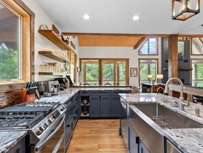 Una cocina moderna con una isla grande, vigas de madera y vistas al exterior.