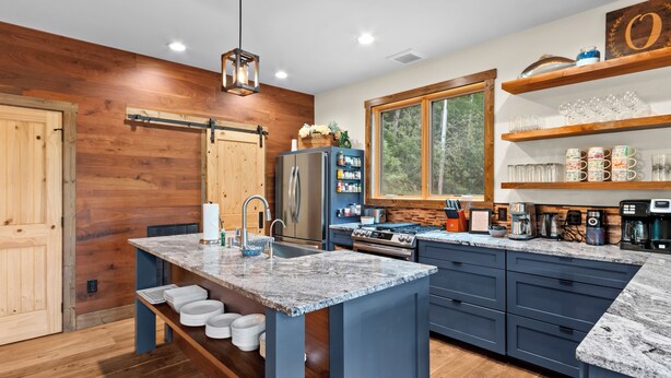 A modern kitchen with a central island, wooden accents, and a large window. - New Home on South Toe River, Pet Friendly (Burnsville)