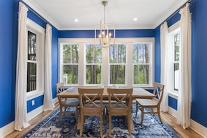 A dining room with a large window, a chandelier, and a blue and white color scheme.