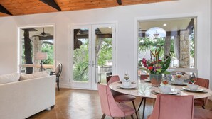 Un comedor amplio con una mesa redonda, sillas rosas y un sofá blanco.