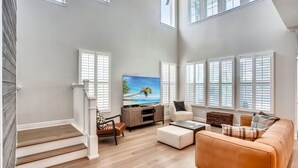 A spacious living room with a large TV, comfortable seating, and a staircase leading to upper floors.