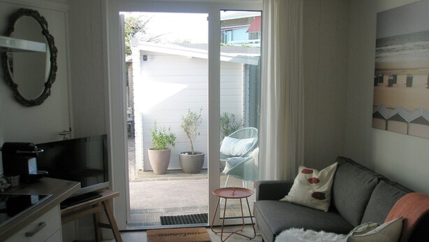 A compact living space with a kitchenette, a sofa, a coffee machine, and a view of the outside. - Luxury apartment for beach/walking  3 minute walk to the beautiful sandy beach. (Egmond aan Zee)
