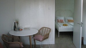 A small room with a bed, a white door, and a round table with chairs. - Luxury apartment for beach/walking  3 minute walk to the beautiful sandy beach. (Egmond aan Zee)