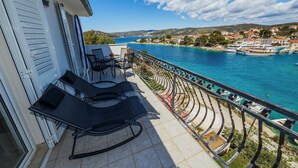 A balcony with two lounge chairs, a small table, and a view of a coastal town and sea. - Goreta in Ražanj - Mittel-Dalmatien / Goreta in Ražanj - Appartement für 4 Personen AP2 (Ražanj)
