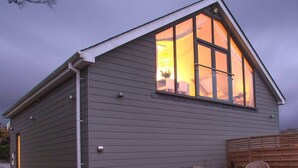 A single-story building with a sloped roof and a large window. - The Neyth (Mabe Burnthouse)