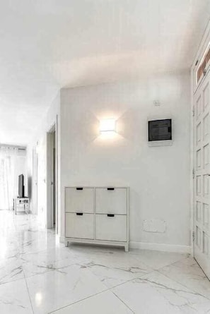 Ein Korridor mit einem weißen Schrank, einer Wandleuchte und einer Tür rechts.