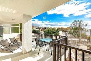A balcony with a table and chairs, a view of the cityscape, and a clear sky. - Moderno apartamento en el Parque Royal I (Adeje)
