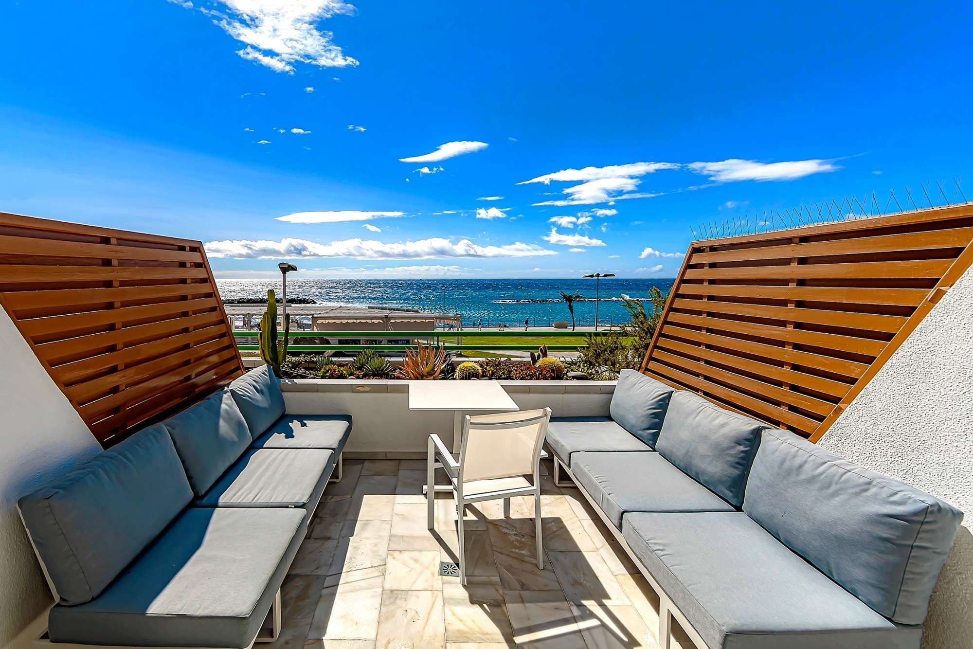 Un área de estar al aire libre con vista al mar, que incluye un sofá y una mesa.