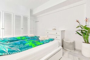 A bedroom with a bed, a white dresser, a plant, and a window with shutters. - Apartment in complex Altamira with direct sea view (Costa Adeje)