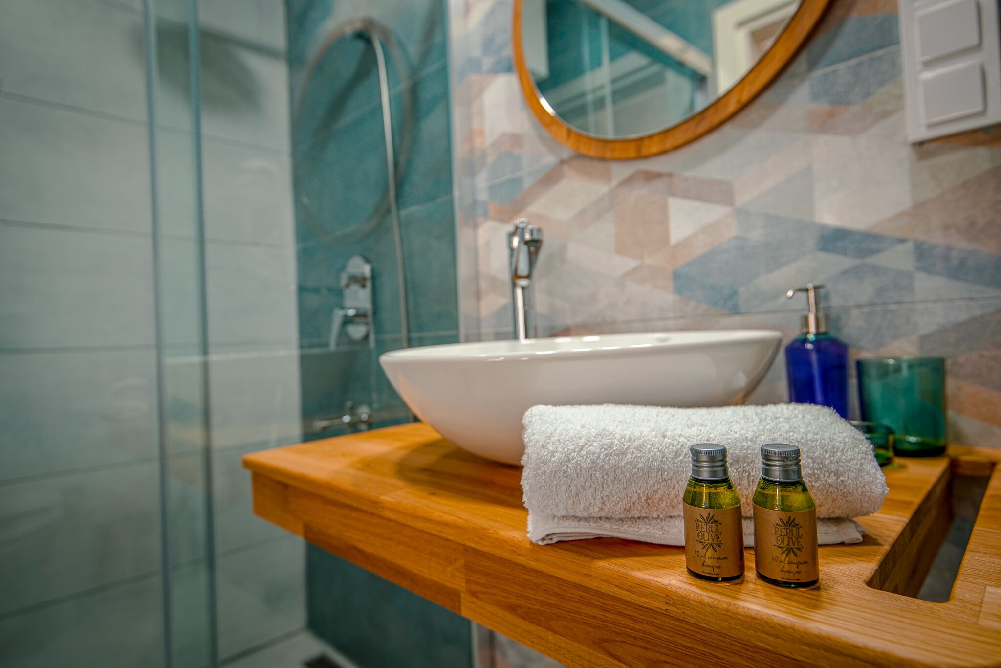 A bathroom with a white sink, a wooden countertop, a white towel, and two bottles of olive oil.