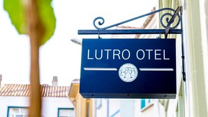 Placa para "LUTRO OTEL" com logotipo mostrando duas figuras e uma taça de vinho.