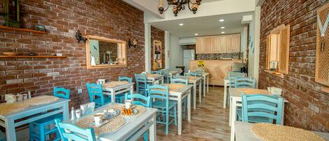A dining area with brick walls, wooden tables, and blue chairs.