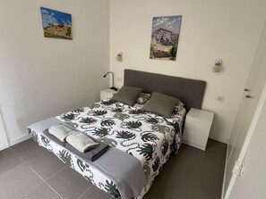 Une chambre à coucher comprenant un lit, des tables de chevet, une lampe et deux appliques murales.