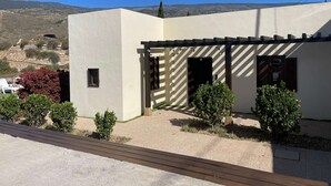 A modern building with a flat roof, a pergola, and a small garden area with shrubs. - Casa rural con vistas maravillosas en Arico (Santa Cruz de Tenerife)