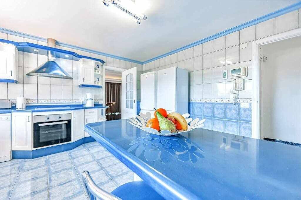 A kitchen with white cabinets, a blue countertop, and a fruit bowl on the island.