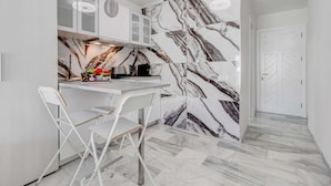 A modern kitchen with marble backsplash, white cabinetry, and a dining area with white chairs. - Graceful brand new studio in Altamira (Adeje)