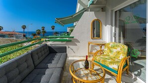 A balcony with a sofa, a wicker chair, and a table with a bottle and glasses. - Graceful brand new studio in Altamira (Adeje)