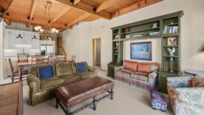 A spacious living area with wooden beams, a dining table, and a green bookshelf. - Snowmass Getaway Wraparound Decks & Valley Views - 229 #35 by RedAwning (Snowmass Village)