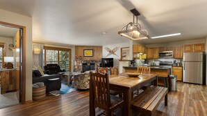 A spacious kitchen with wooden cabinets, a dining table, and a stone fireplace.