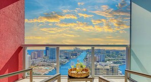 A balcony with a cityscape view, a table with a basket, and a bottle. - Lovely Apartment, Balcony View, Amazing Pool (Hallandale Beach)