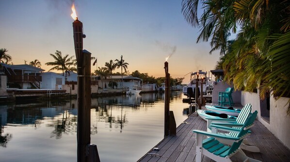 A calm waterfront area with docked boats, a wooden deck, and lounge chairs. - **MARINER’S HIDDEN HAVEN** Waterfront & Pool + Last Key White Glove Service... (Key West)
