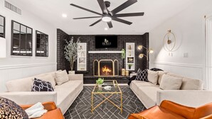 Un salon moderne avec une cheminée, deux canapés, une table basse et un ventilateur de plafond.