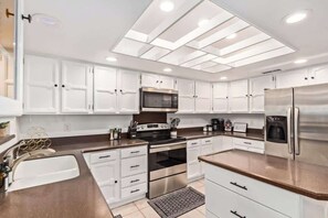 A modern kitchen with white cabinets, stainless steel appliances, and a skylight. - Tiki Paradise w/Htd. Pool, Putt Grn. & Tiki Bar (Phoenix)