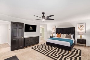 A modern bedroom with a bed, a ceiling fan, a TV, and a dark-colored wardrobe. - Tiki Paradise w/Htd. Pool, Putt Grn. & Tiki Bar (Phoenix)