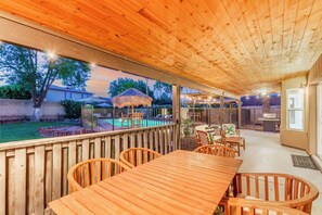 A covered outdoor area with a wooden table and chairs, a pool, and a barbecue grill. - Tiki Paradise w/Htd. Pool, Putt Grn. & Tiki Bar (Phoenix)