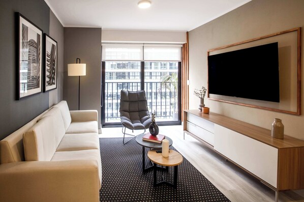 A modern living room with a sofa, a chair, a coffee table, a TV, and artwork on the walls.