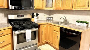 A kitchen with wooden cabinets, a Bosch stove, a microwave, a sink, and a dishwasher. - Swan River Cottage - Near Beach, Water View, Kayak, (Dennis)