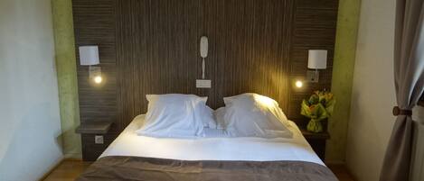 A neatly made bed with white linens, two bedside lamps, and a wooden headboard.
