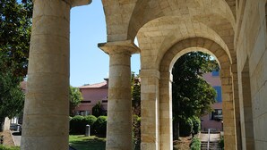 A stone archway with a clear view of a building in the background. - Hotel Restaurant des Thermes (Castera-Verduzan)
