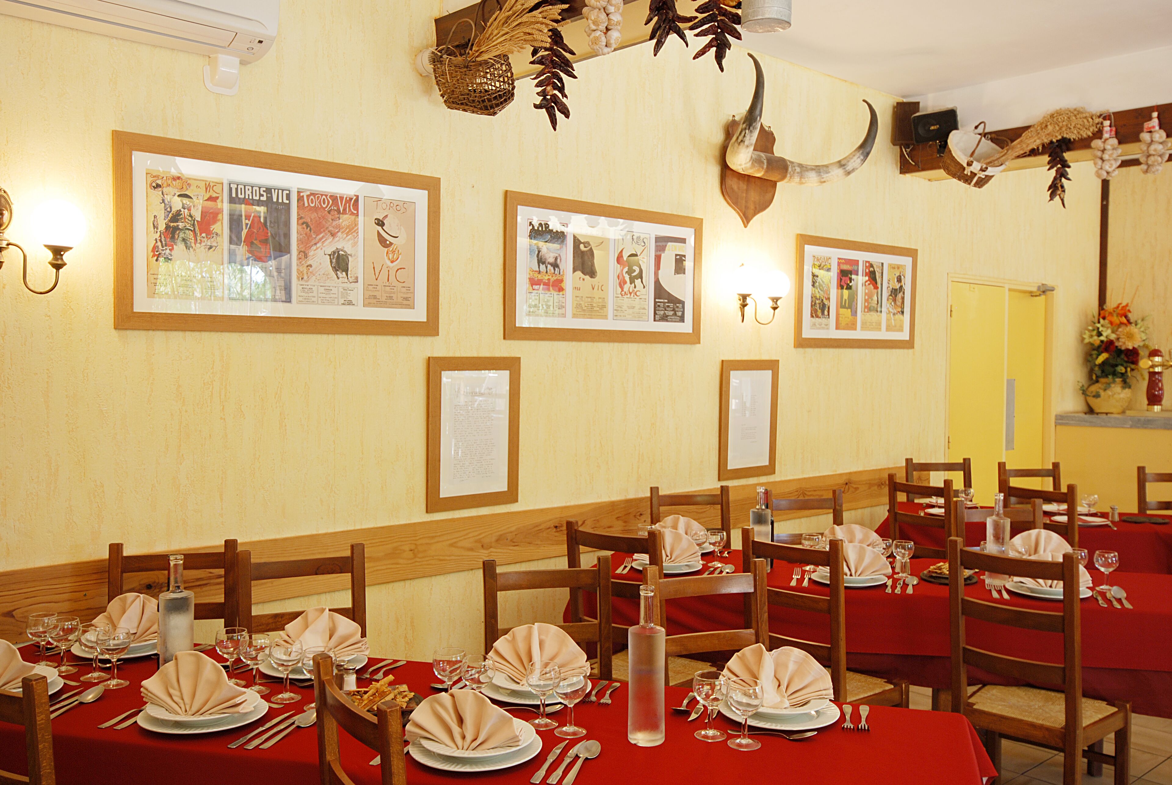 Un restaurante con manteles rojos, sillas de madera y cuadros en la pared.