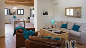 A living room with a sofa, coffee table, and a dining area with chairs and a table. - Villa Elettra 12+2 by Marche Holiday Villas (San Costanzo)
