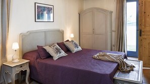 Une chambre à coucher avec un lit, une table de chevet, une armoire et une fenêtre.