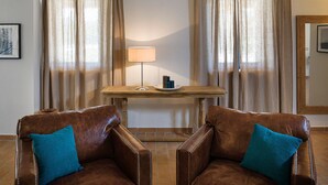 A room with two leather armchairs, a wooden table with a lamp, and a plate with candles. - Villa Elettra 12+2 by Marche Holiday Villas (San Costanzo)