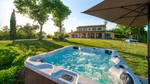Un jacuzzi dans un jardin, avec une maison en arrière-plan.