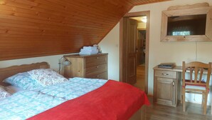 Um quarto com uma cama, cômoda de madeira, escrivaninha e uma cadeira.