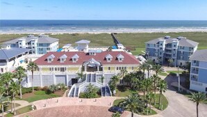 A coastal hotel with multiple buildings, a central staircase, and a beach view. - Seas The Day-Front Row-Beach Front-Next to Beach Club-3BD/2BA. Sleeps 8 (Galveston)