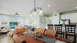 A dining area with a wooden table, woven chairs, and a chandelier. - Seas The Day-Front Row-Beach Front-Next to Beach Club-3BD/2BA. Sleeps 8 (Galveston)