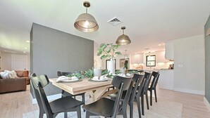 A modern dining area with a wooden table, black chairs, and pendant lighting. - Bayside Oasis with Hot Tub & Game Room (Dennis)