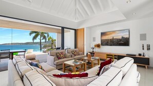 Uma sala de estar moderna com um sofá grande, mesa de centro e vista para o mar.