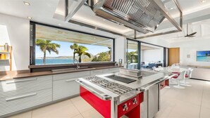 Cozinha moderna com uma ilha grande, vista para o mar e área de jantar também com vista.