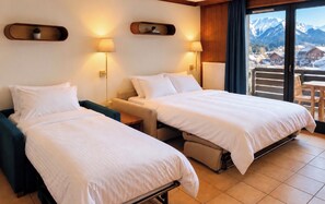 A hotel room with two beds, a balcony with a view of mountains, and a wooden ceiling.