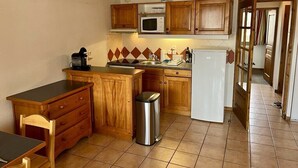 A compact kitchen with wooden cabinets, a microwave, a coffee maker, and a trash bin. - Nice flat with balcony view Mont Blanc | Parking (Chamonix-Mont-Blanc)